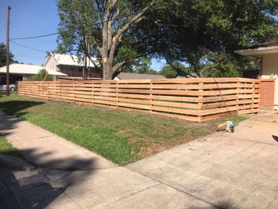 Modern horizontal wooden fence with concrete driveway
