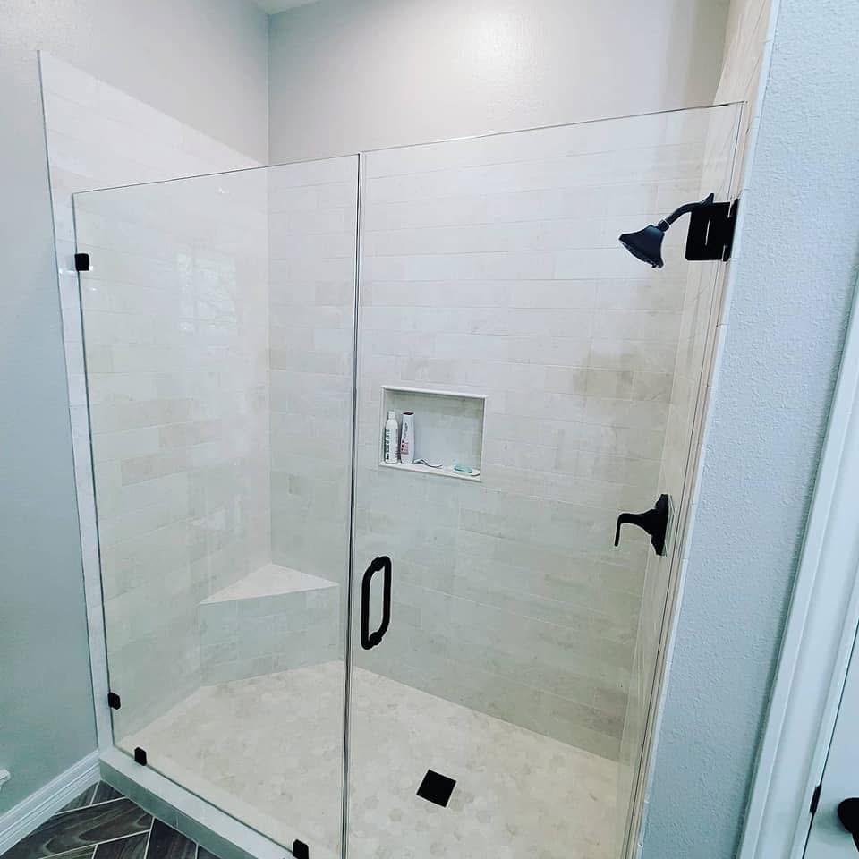 Frameless glass shower with white tile walls and black fixtures